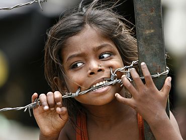 A child bites a barbed wire after a slum fire gutted dozens of huts in New Delhi