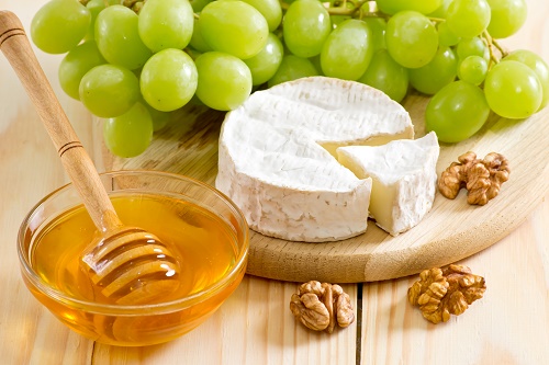 Still life of cheese, honey, walnuts and grapes